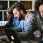 Professionals concentrate on projects in a contemporary office setting using laptops.