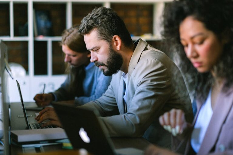 Professionals concentrate on projects in a contemporary office setting using laptops.